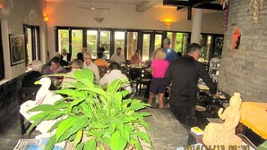 Un restaurant doté d’une salle à manger, de grandes fenêtres et d’un arrangement floral central.
