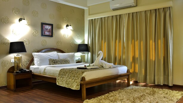 A neatly made bed with a swan-shaped pillow, a bedside lamp, and a framed picture on the wall.
