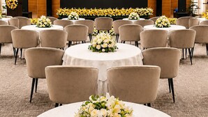 A conference room with multiple round tables, each with a floral centerpiece, arranged in rows.