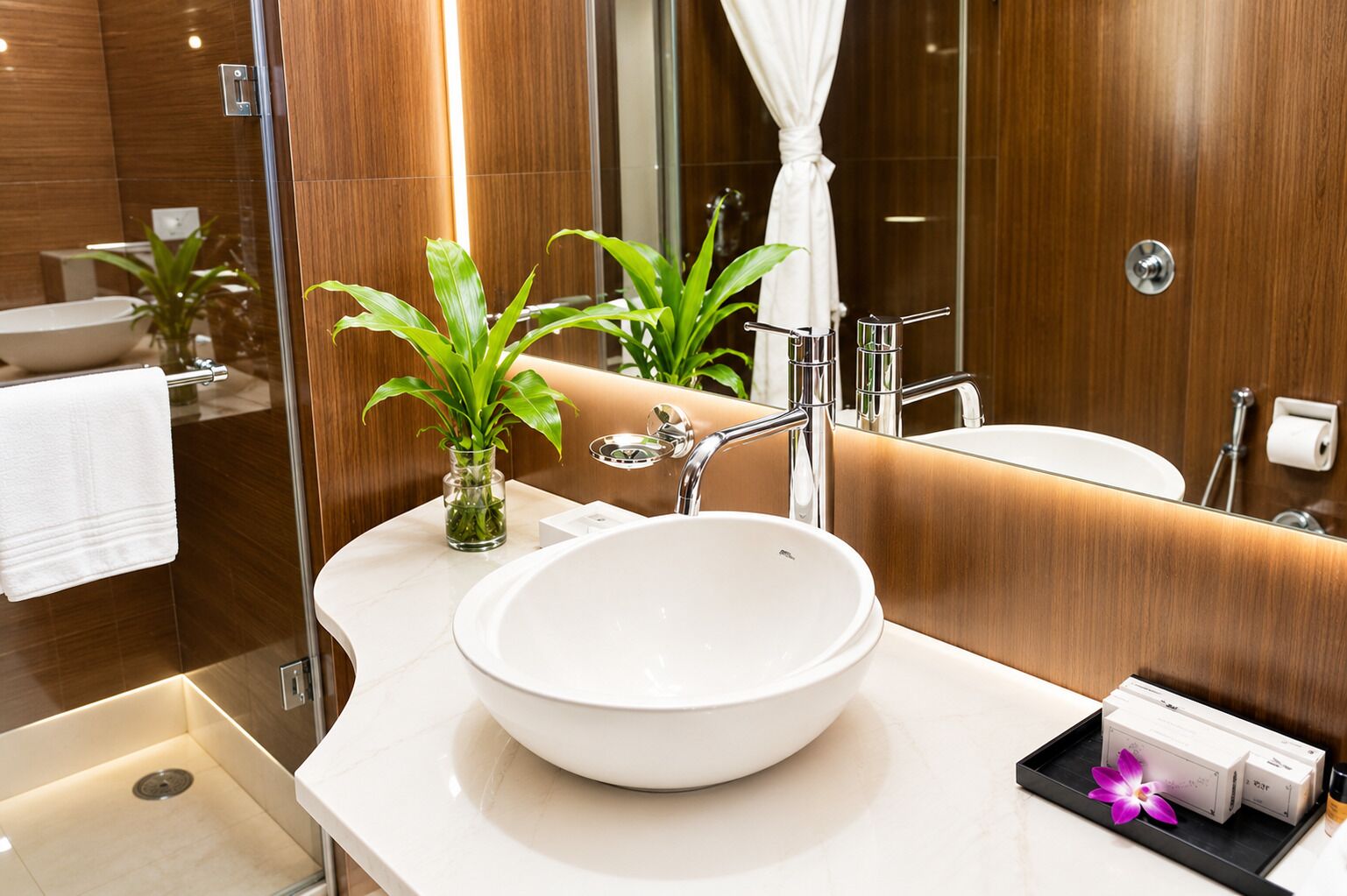 A modern bathroom with a large white sink, a glass shower enclosure, and a mirror reflecting the room.