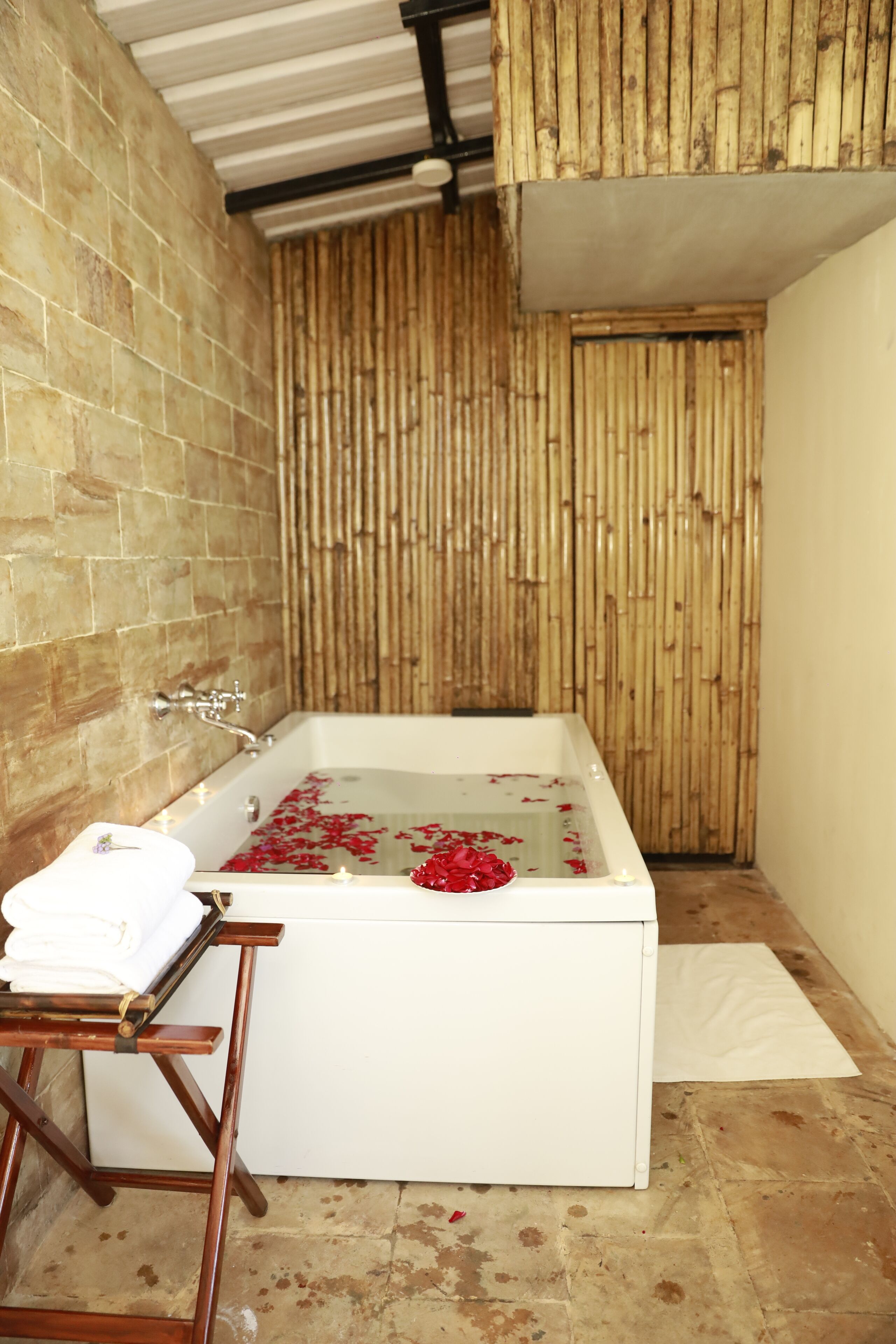 A bathroom with a bathtub, a wooden wall, and a tiled floor.