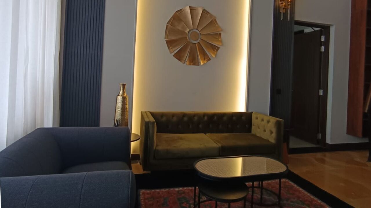 A modern living room with a dark blue sofa, a brown sofa, a round coffee table, and a decorative wall piece.