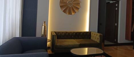 A modern living room with a dark blue sofa, a brown sofa, a round coffee table, and a decorative wall piece.