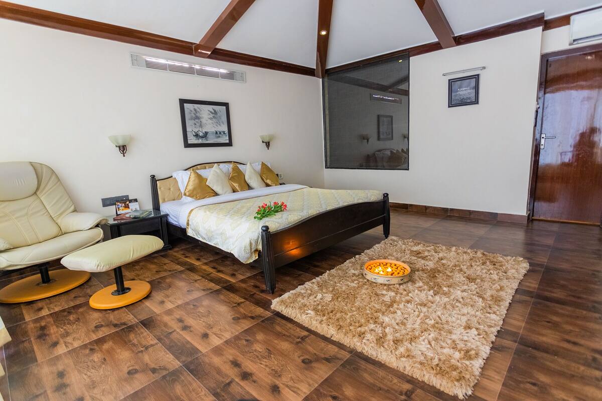 Ein Schlafzimmer mit einem Bett, einem Sessel, einem Nachttisch, einem Teppich und Holzboden.