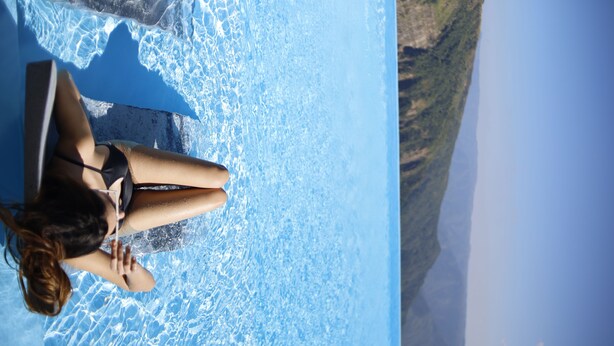 A woman sitting by a pool with a clear view of the surrounding landscape. -  Polo Cherrapunjee Resort  (Shillong)