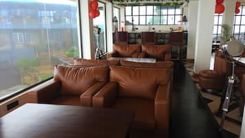 Ein modernes Interieur mit Ledersofas, einem Holztisch und einer Küchenzeile mit Barhocker.