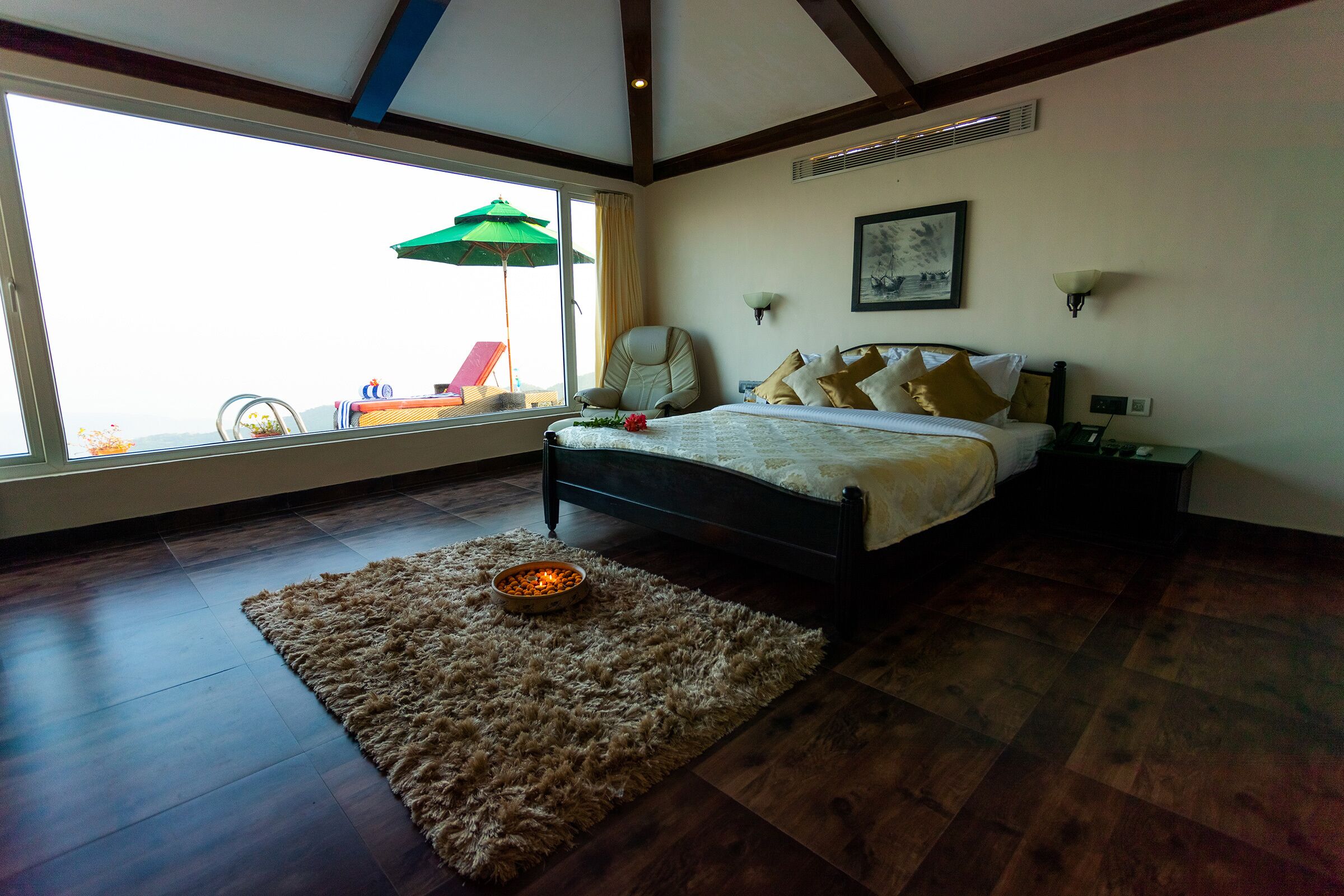 A bedroom with a large window, a bed, a chair, a rug, and a nightstand.
