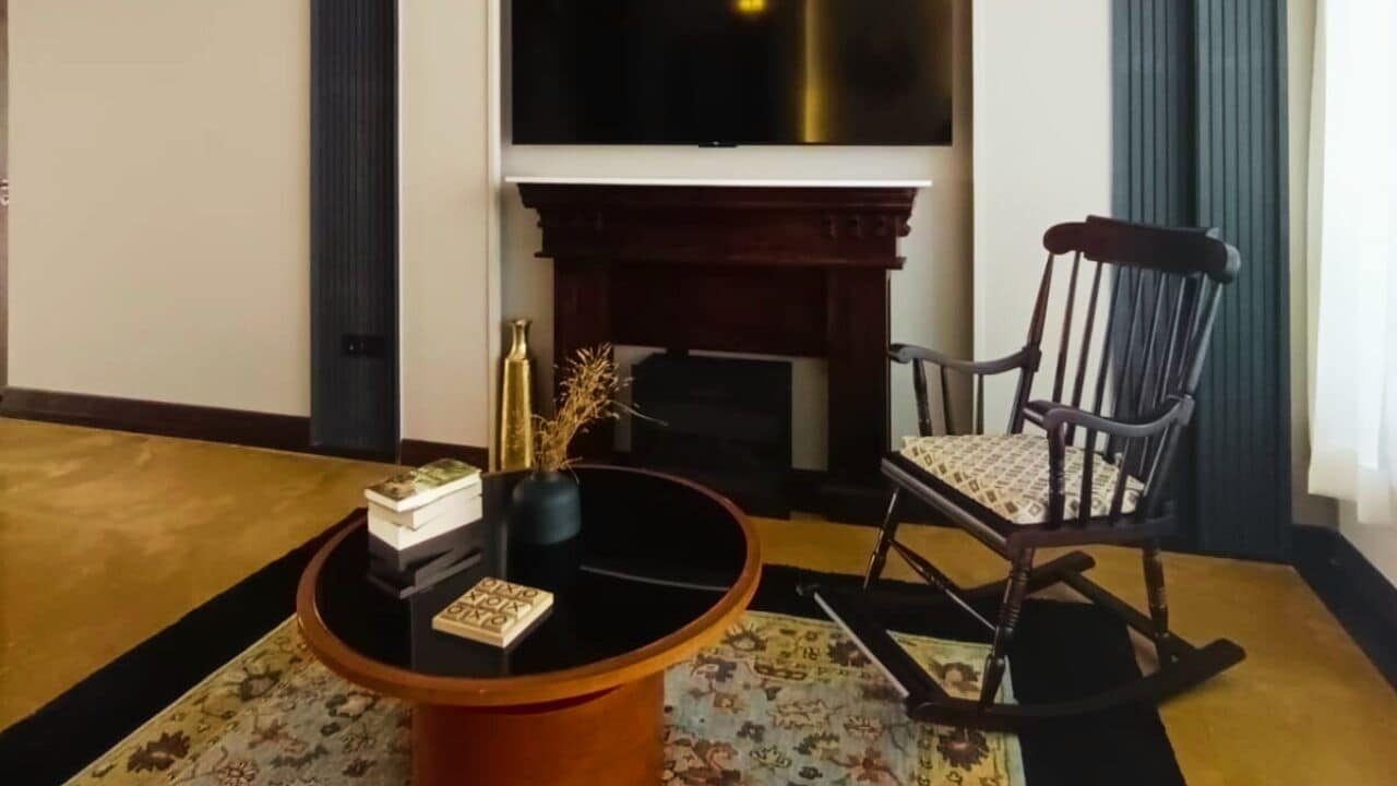 A living room with a fireplace, a television, a rocking chair, and a coffee table with decorative items.