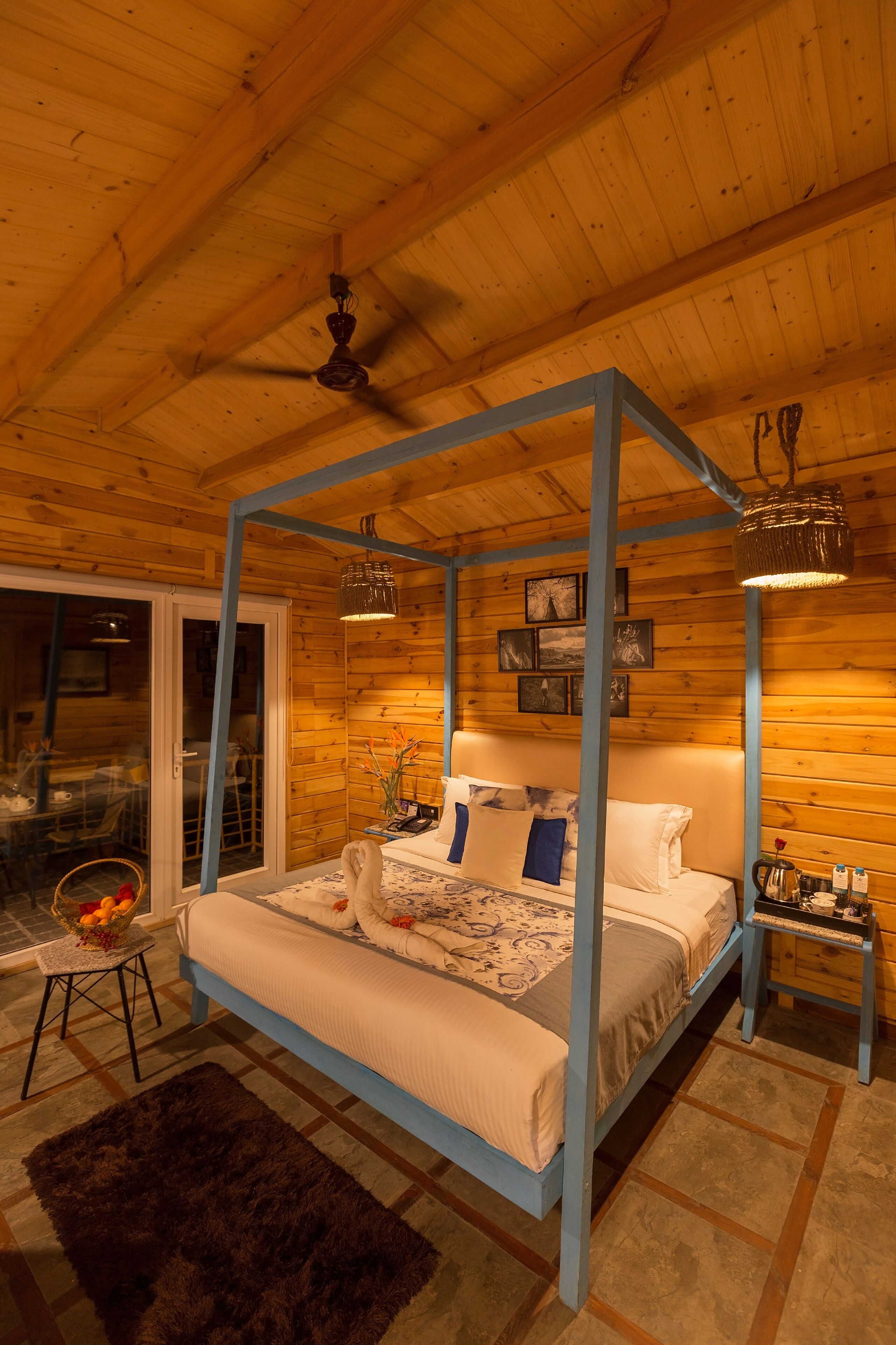 A four-poster bed with a wooden ceiling and a view of the outside through a sliding glass door.