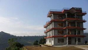 Un immeuble à plusieurs étages doté de balcons, situé sur une colline et offrant une vue sur le paysage environnant.