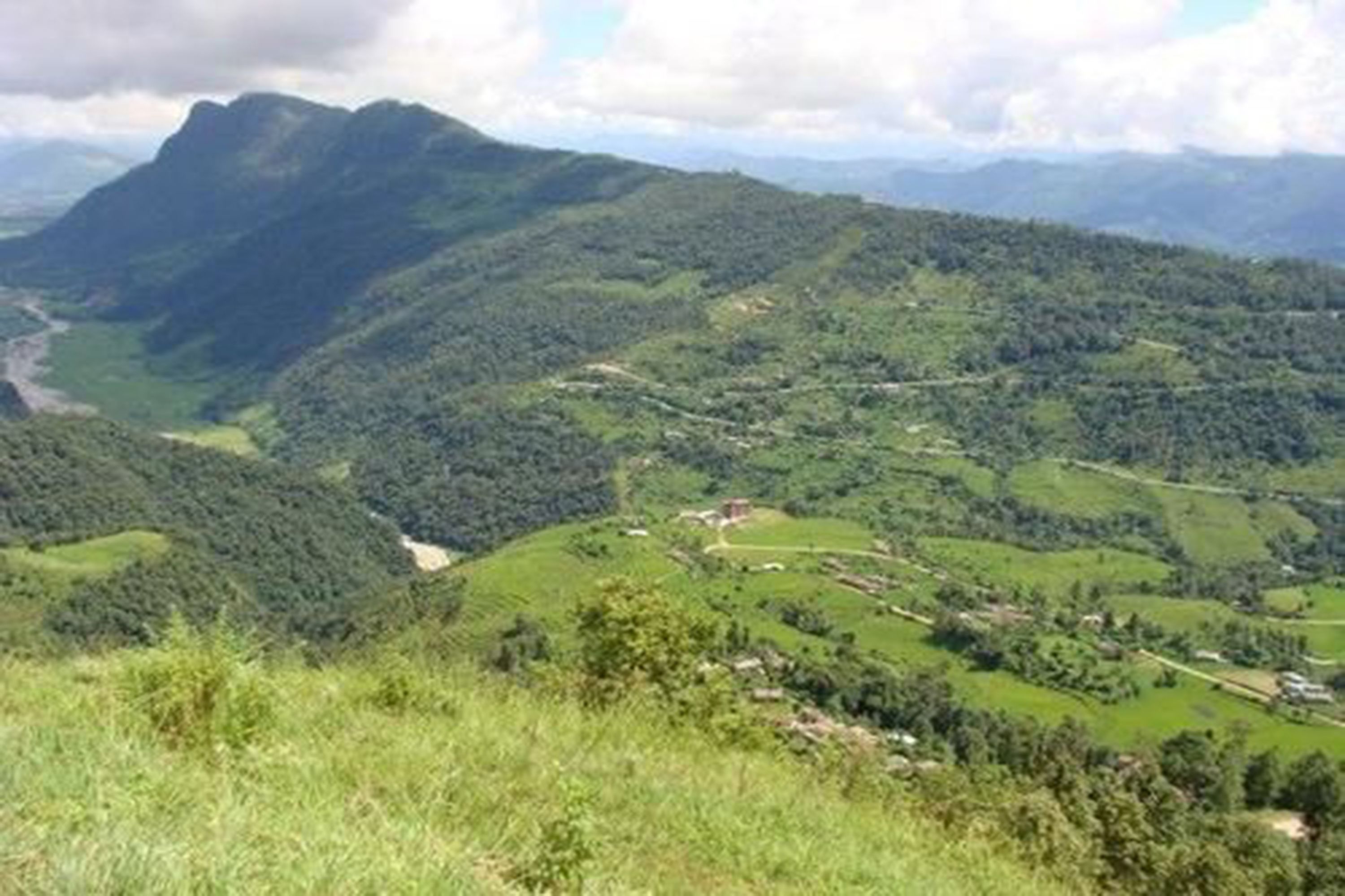 A mountainous landscape with a winding road and scattered buildings.