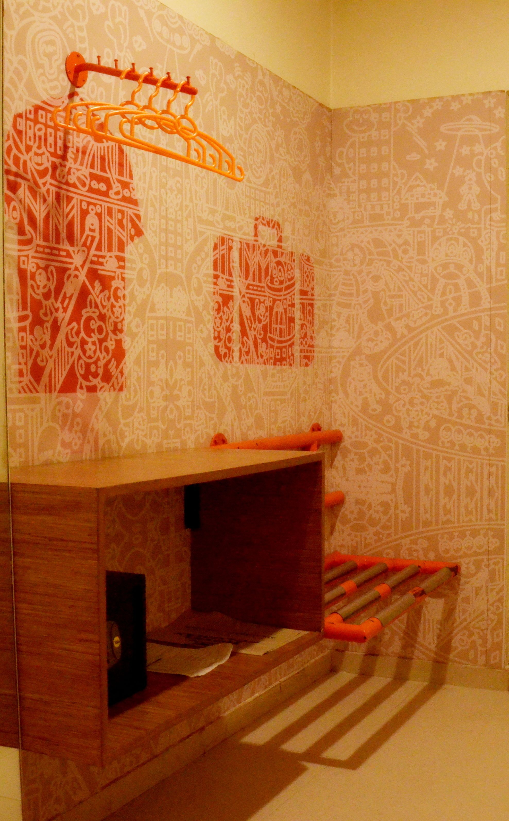 Un baño con tocador de madera, un perchero y papel tapiz estampado.
