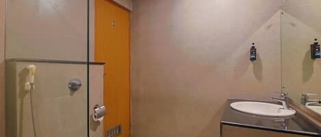 A compact bathroom with a toilet, a glass shower enclosure, a sink, and a wooden door.