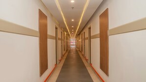 Un largo y estrecho pasillo de hotel con paneles de madera en las paredes, piso gris y barandas naranjas.