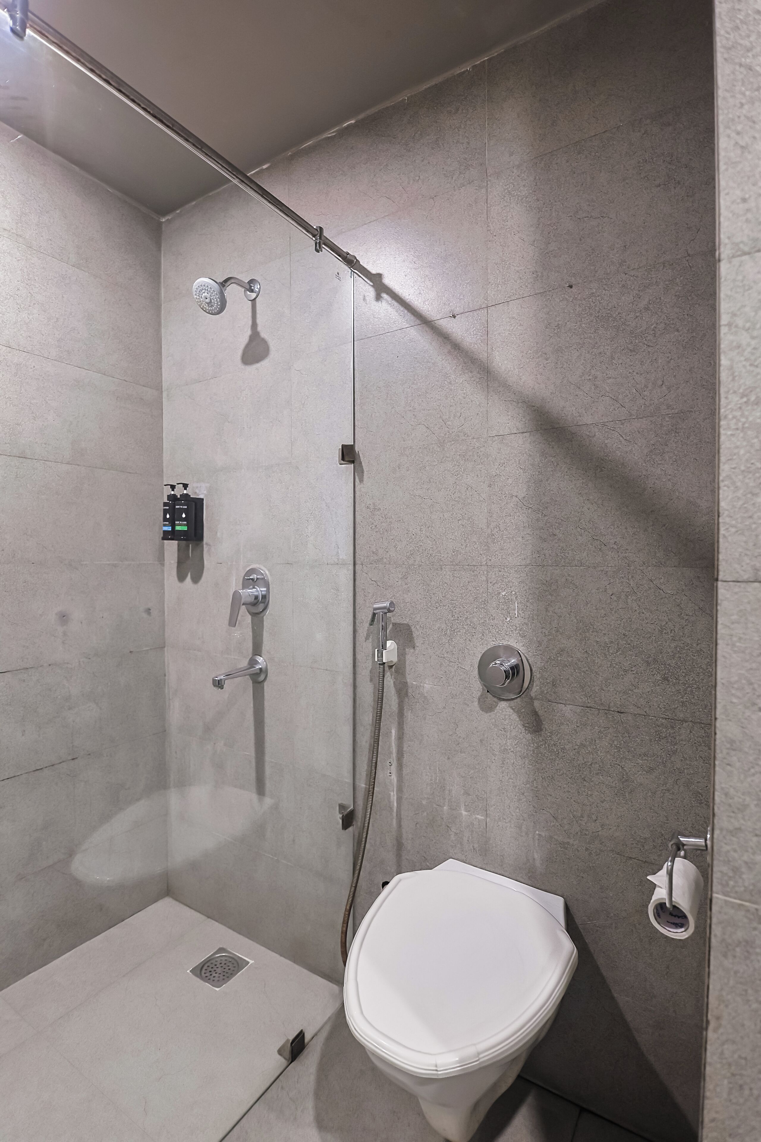 A modern bathroom with a shower, toilet, and control panel.