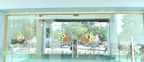 A hotel entrance with a glass facade, potted plants, and a sign reading "HOTELPOLOMAX.COM".