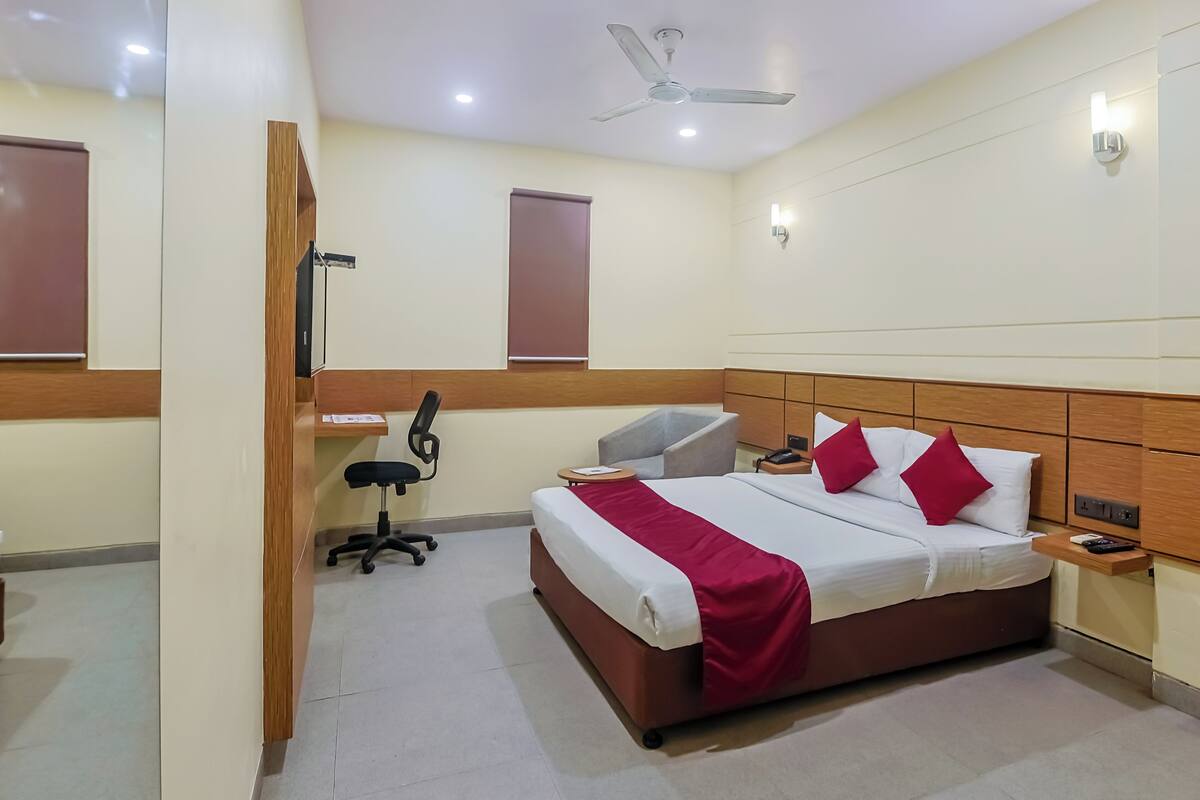 Habitación de hotel con cama, escritorio, silla y ventilador de techo.