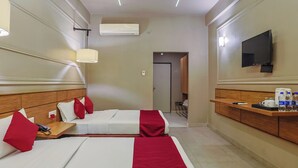 Habitación de hotel con dos camas, televisión, mesita de noche con teléfono y pequeña zona de kitchenette.