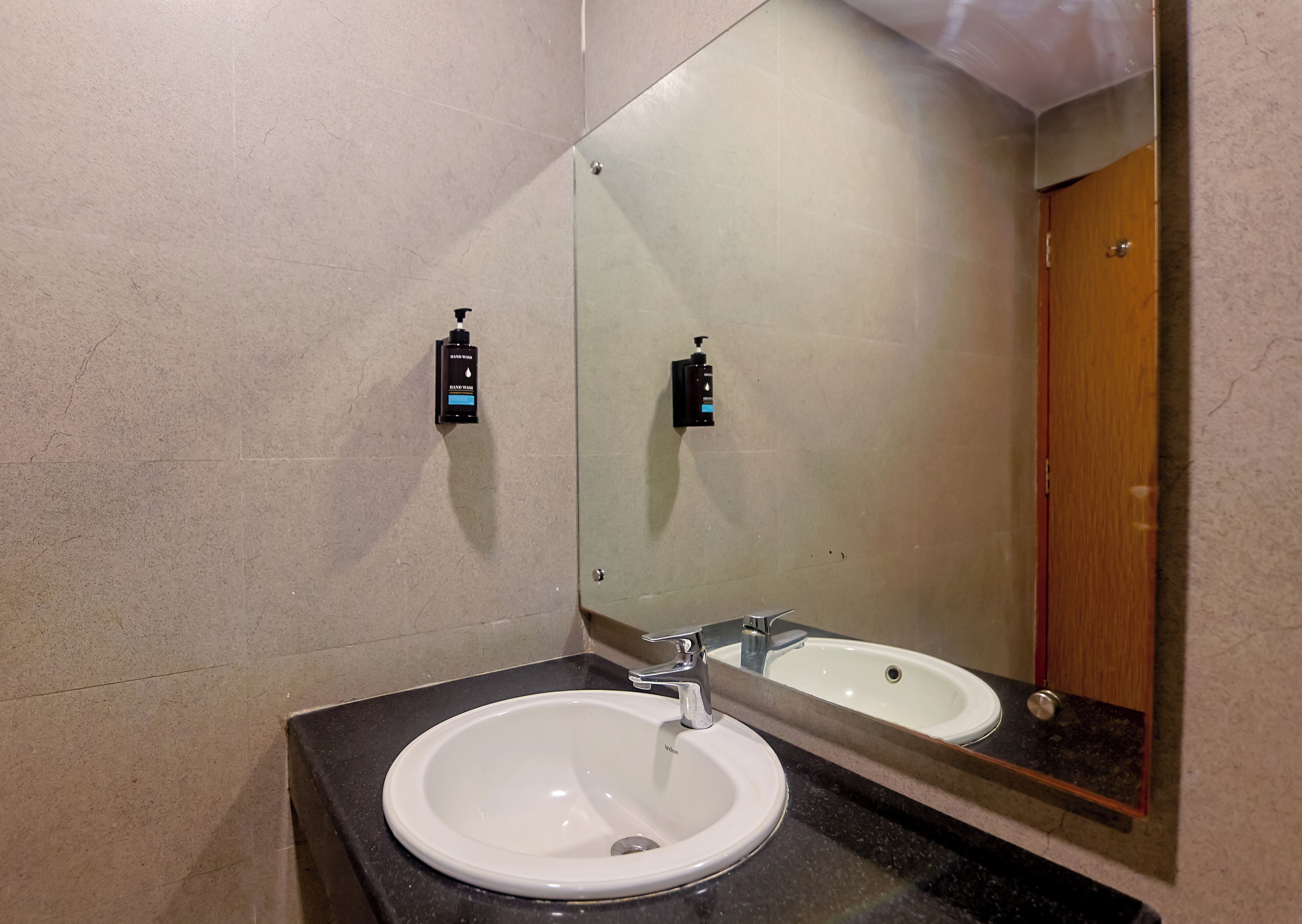 A bathroom with a white sink, a mirror, and two soap dispensers mounted on the wall.