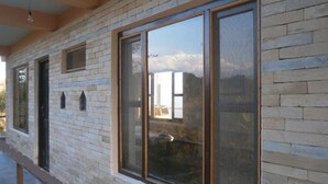 A building facade with large windows, a brick wall, and a wooden ceiling. - Green Park (Pokhara)