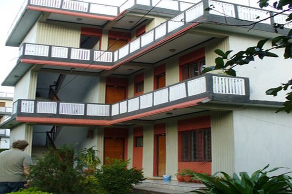 A multi-story building with balconies, a staircase, and a small garden area.