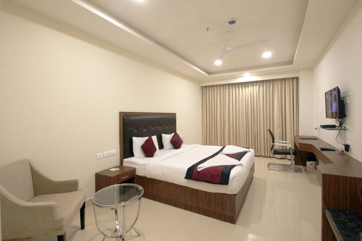 A hotel room with a bed, a desk, a chair, and a television.