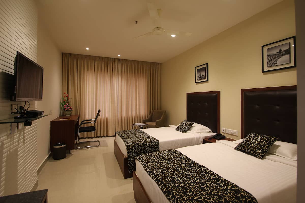 A hotel room with two beds, a TV, a desk, and a chair.