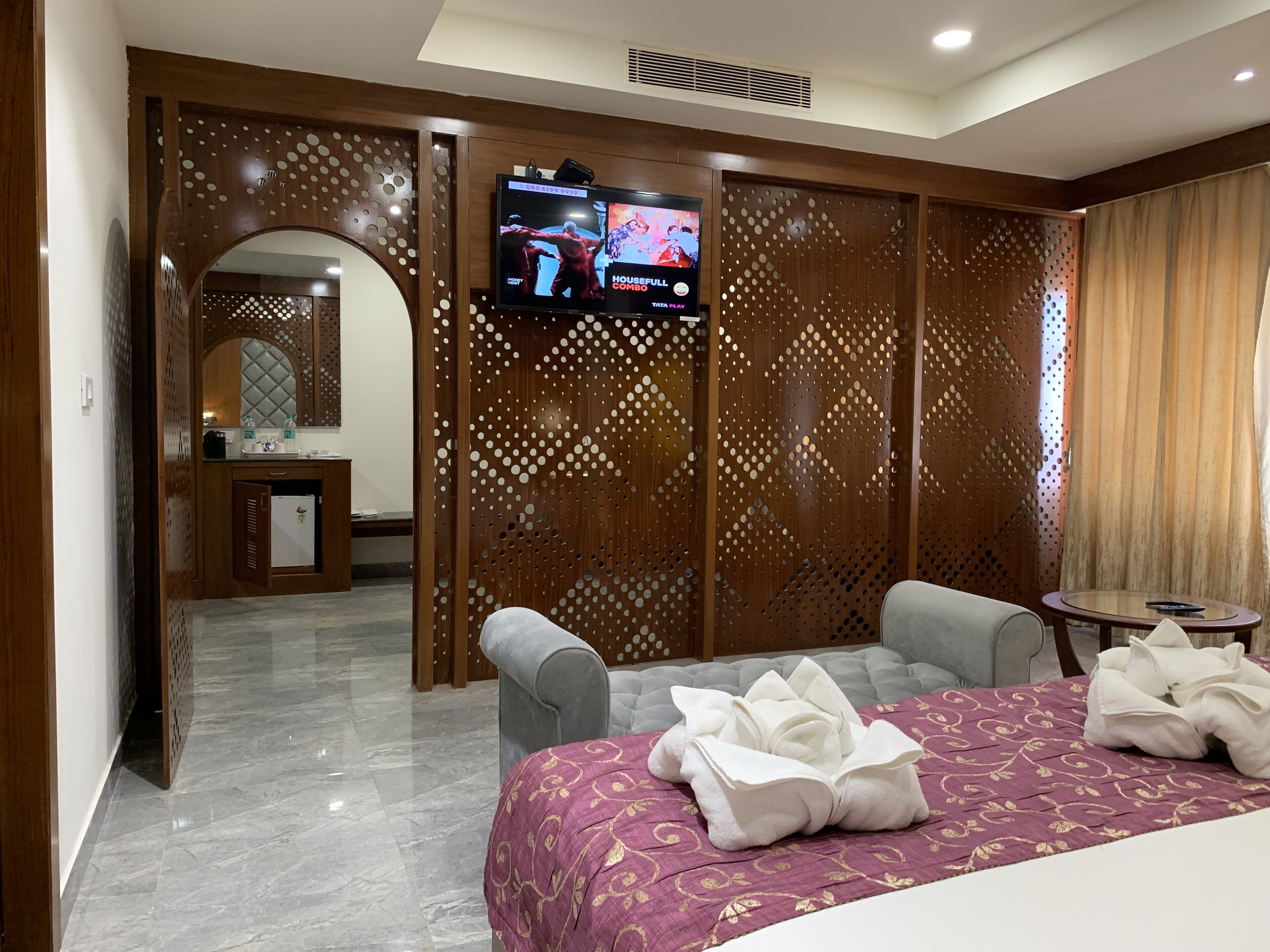 A hotel room with a bed, two armchairs, a TV, and a small table.