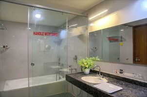 A modern bathroom with a glass-enclosed shower, a sink with a mirror, and a potted plant on the counter.