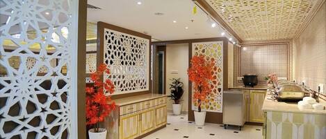 Un moderno vestíbulo de hotel con una recepción, paneles decorativos y una zona de buffet.