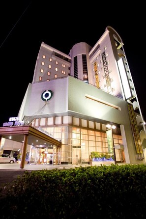 Un hotel de varios pisos con un logotipo circular llamativo en la fachada, ventanas amplias y una entrada bien iluminada.