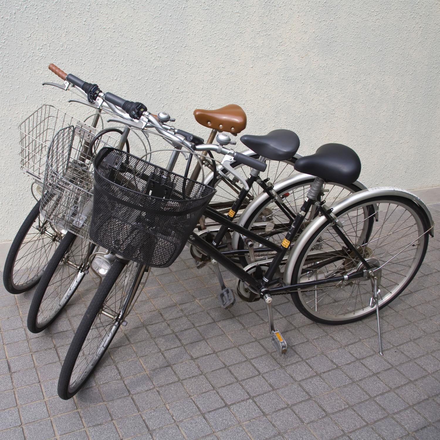 A bicycle with a basket and a rear rack, parked against a wall.