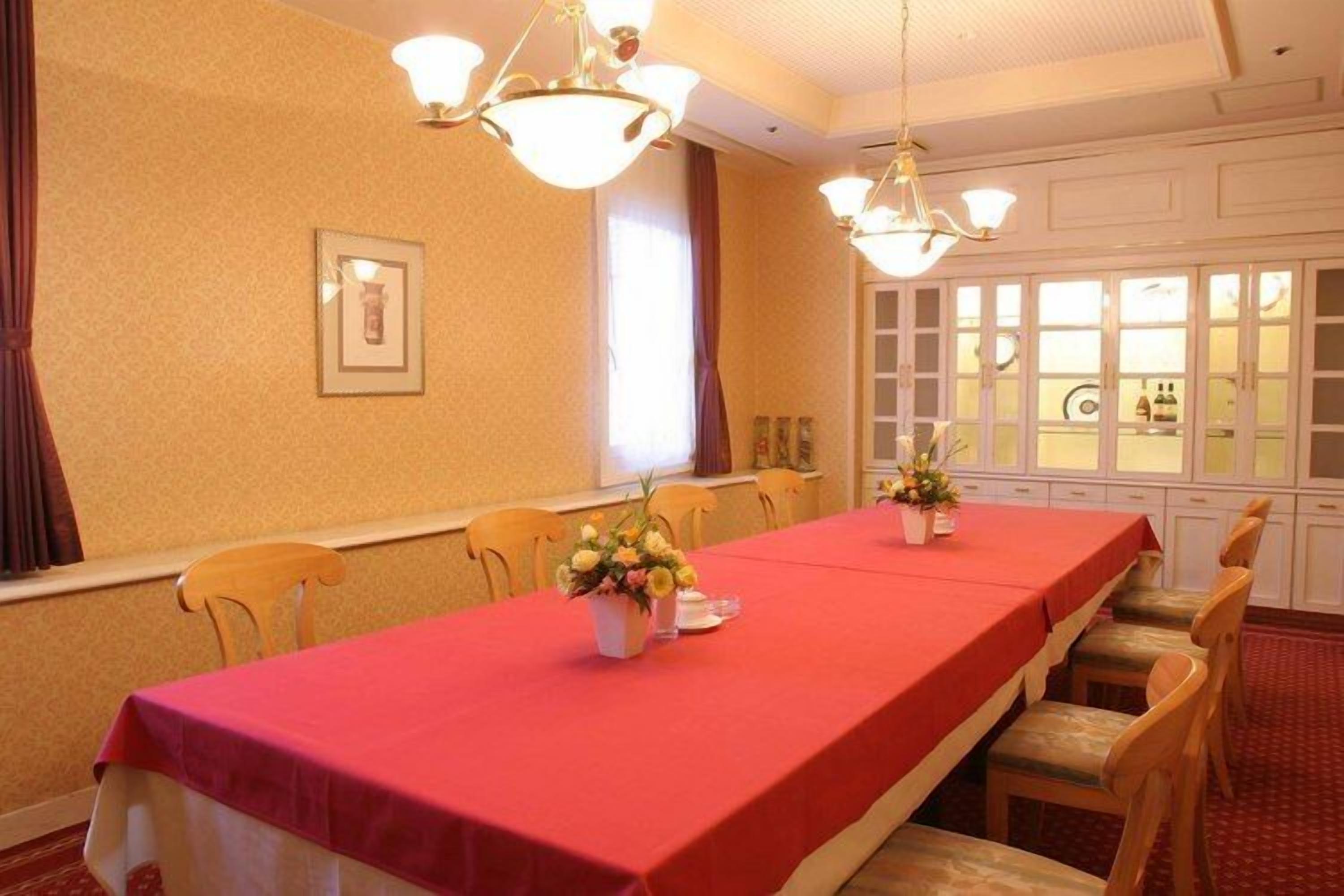 Une salle de conférence avec une longue table, des chaises et des lustres.