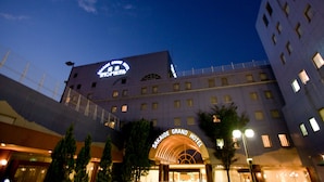 The exterior of the Sakaide Grand Hotel at night, featuring a prominent sign and a modern architectural design.