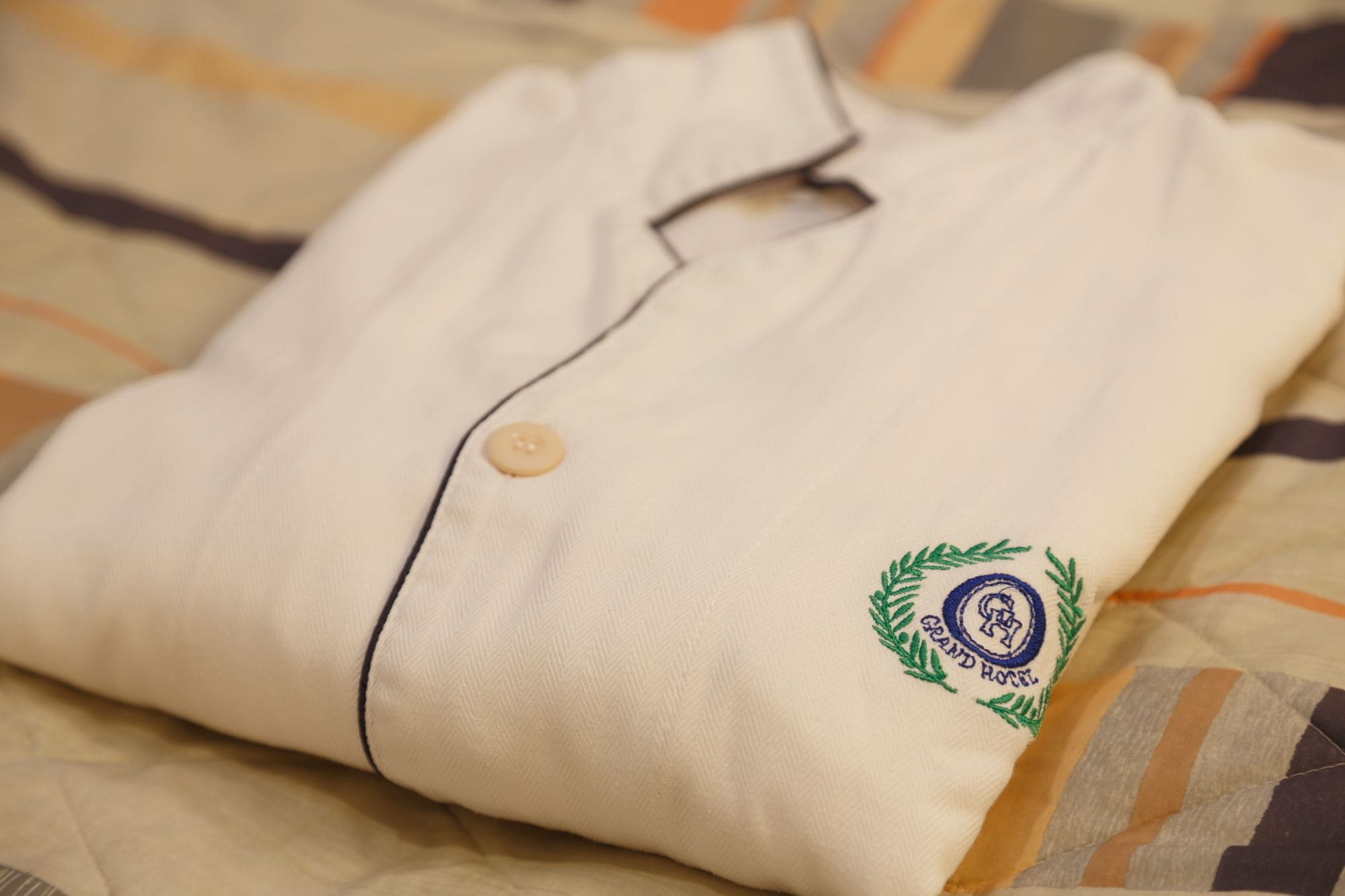 A neatly folded white shirt with a button and a logo on the pocket.