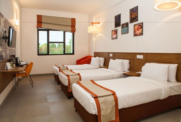 Una habitación de hotel con tres camas, un escritorio y una silla.