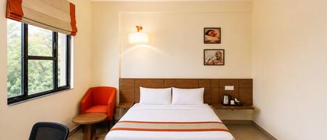 A hotel room with a bed, a desk, a chair, a nightstand, and a ceiling fan.
