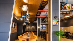 A restaurant with a long wooden table, orange chairs, and pendant lighting. - Max Hotels Jabalpur (Jabalpur)