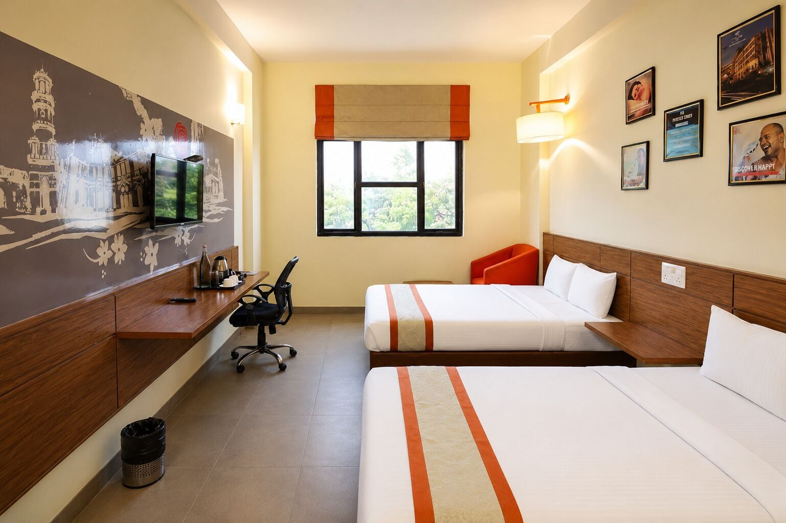 A hotel room with a bed, a desk, a chair, a trash bin, a window with a view, and wall decorations.