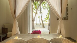 A bedroom with a bed, curtains, and a view of the beach. - Les Maisons D'itac (Ronda)