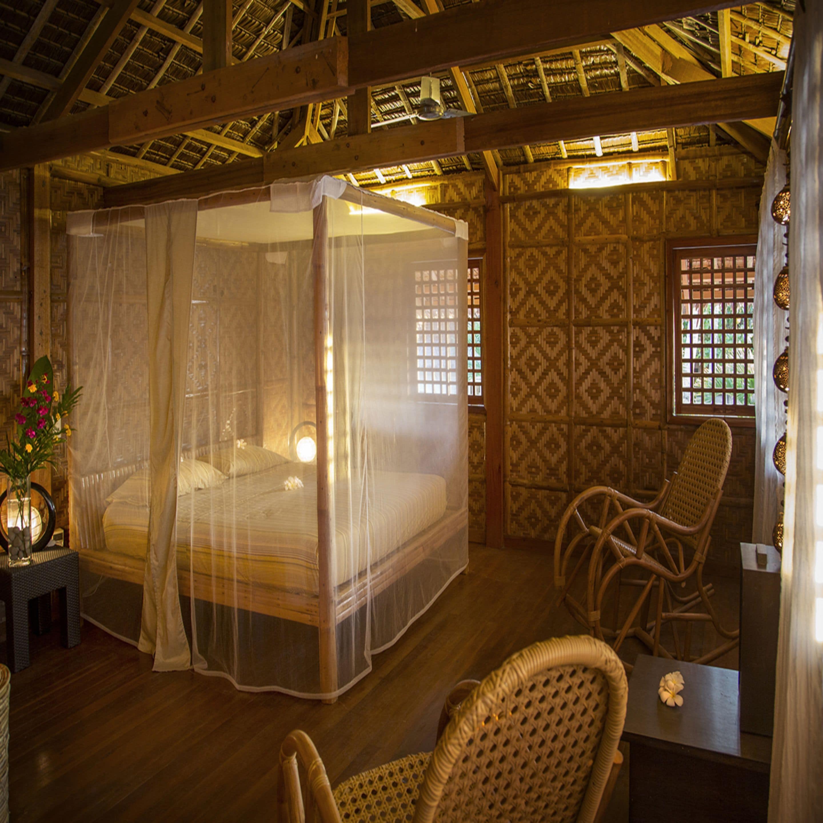 A room with a four-poster bed, a chair, and a table.