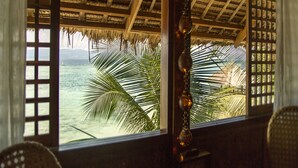 A room with a view of the ocean through a window with a thatched roof and wooden lattice. - Les Maisons D'itac (Ronda)