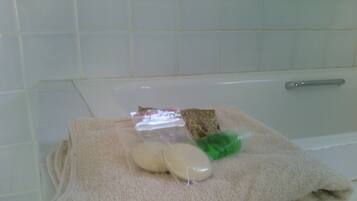 Un baño con una bañera blanca, una toalla, un jabón y una pequeña bolsa de plástico.