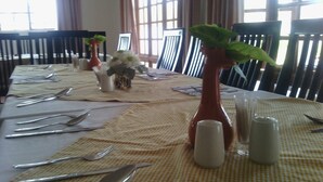A dining table set with cutlery, salt and pepper shakers, and a vase with flowers. - Moko Motel (Mahalapye)