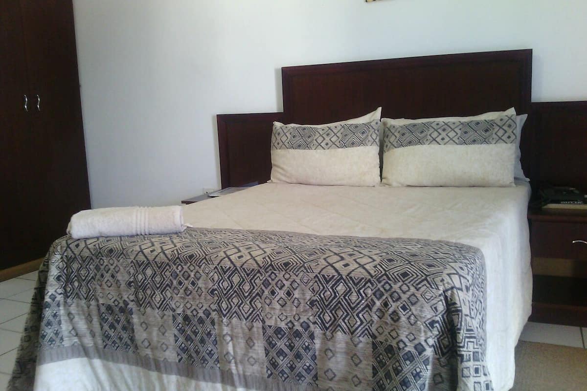 A neatly made bed with patterned bedding and a wooden headboard.