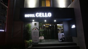 La entrada del Hotel Cellio, con un letrero llamativo, escalones que conducen a la entrada y un arreglo floral en los escalones.