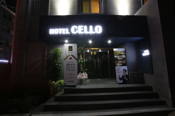 The entrance to Hotel Cellio with a prominent sign, steps leading up to the entrance, and a flower arrangement on the steps. - Hotel Cello Guri (Guri)