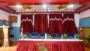 A conference room with a long table, red curtains, and flags. - Hotel Deep Sagar (Pokhara)