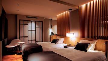 A hotel room with two beds, a desk, a chair, and a wooden panel wall.