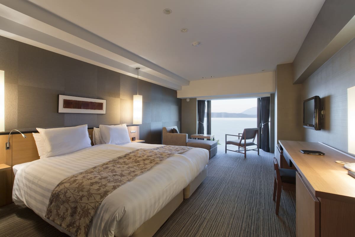 Une chambre d’hôtel moderne équipée d’un grand lit, d’un bureau, d’une chaise et d’un téléviseur.